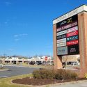 sign showing the names for all the stores in the shopping center on a clear skies day